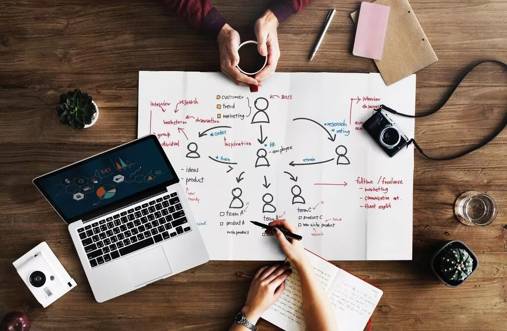 Deux personnes dessinant l'organisation d'un projet sur une table